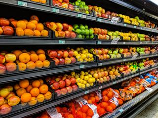 Shelves of yellow and red apples on display in a supermarket